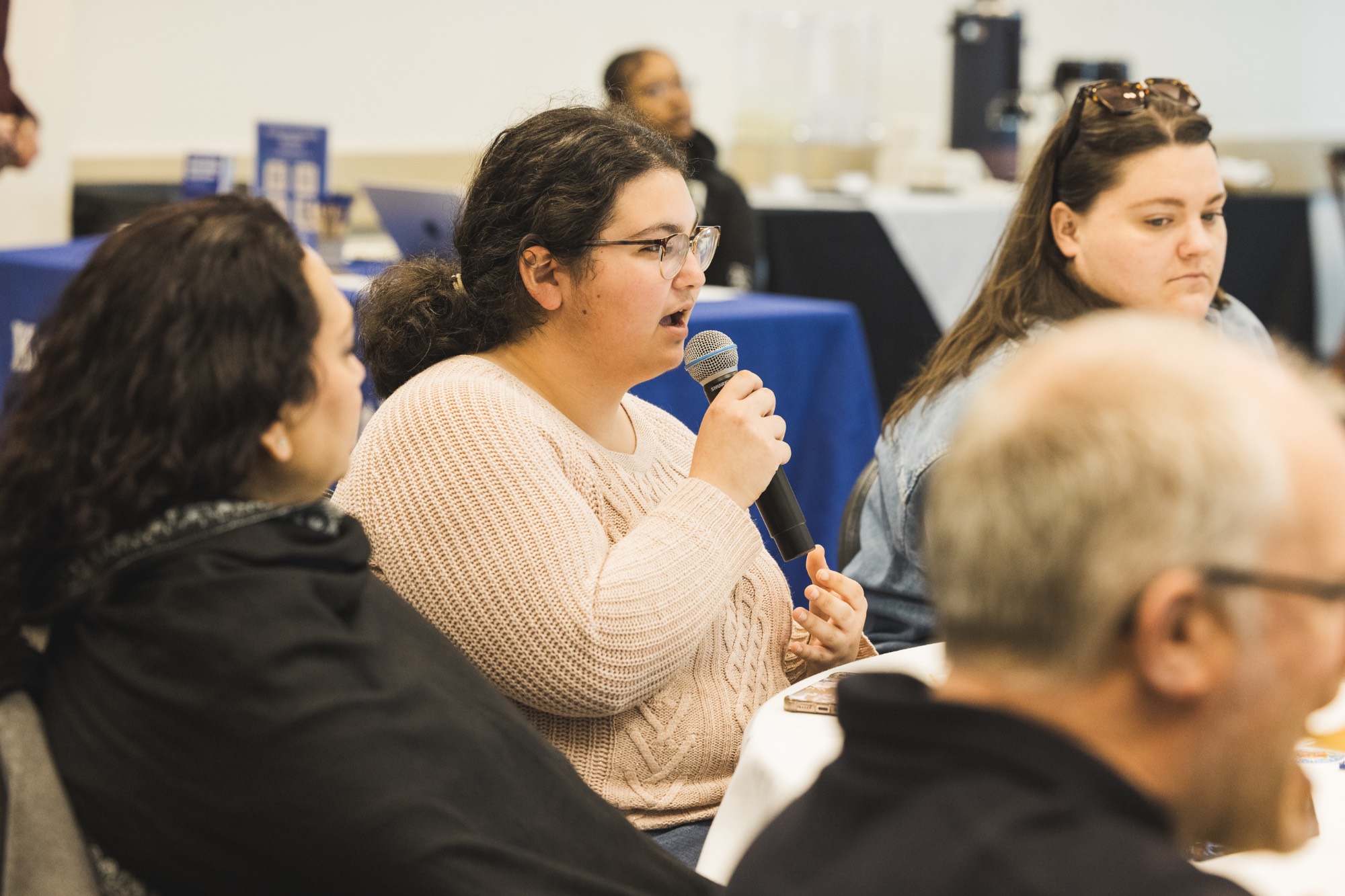 A student with a microphone gesturing and asking a question